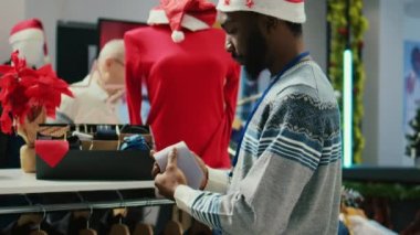 Mutlu Afro-Amerikan işçilerinin Noel süslü, lüks alışveriş merkezleri giyim mağazasında resmi kravat düzenleyip müşterileri için hazır olduklarından emin olmak için yakın plan çekimleri.