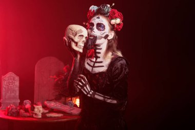La Cavalera Catrina elinde kafatası, elinde siyah güller ve korkunç bir makyajla ürkütücü davranıyor. Çiçekli Santa Muerte 'ye benziyor. Taç ve vücut sanatı, kutsal Meksika kutlaması..