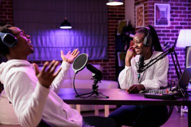 Çevrimiçi şov sunucusu canlı yayında konuklarla röportaj yapıyor. Hayatı hakkında komik hikayeler anlatıyor. Profesyonel araçlarla podcast kaydeden, kadınlarla birlikte gülen bir talk show muhabiri.