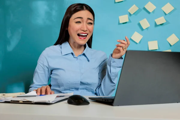 一个乐观的女人坐在写字台前 有一个有趣的视频通话 公司的女员工一边兴奋地大笑 一边与同事遥谈 — 图库照片