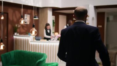 Girişimci lobide resepsiyonistle sohbet ederek otel personeline lüks yardım ve hizmetlerinden ötürü minnettarlıklarını dile getirdi. İş adamı iş gezisinde kolay kontrolü takdir ediyor.