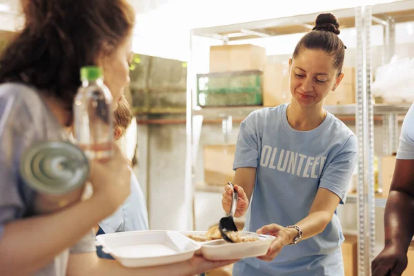 提供帮助 提供热饭和支助有需要的无家可归者和难民的年轻妇女 图为女性慈善工作者向弱势人群提供免费食物的情况 — 图库照片