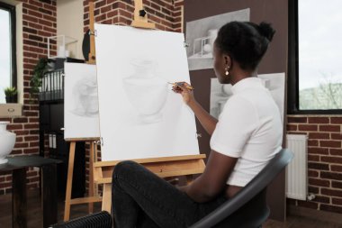 Resim derslerine katılırken resim sehpasında vazo çizen genç Afrikalı Amerikalı bir kadın. Sanat okulunda okurken çizim becerilerini geliştiren bir öğrenci kız. Yaratıcı hobi kavramı