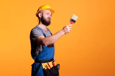 Erkek müteahhit elinde boya fırçasıyla duvarları boyuyor, yenileme projesi üzerinde çalışıyor ve aletlerle resim yapıyor. İnşaat işçisi ressam fırça ve boyayla tadilat yapıyor..