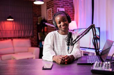 Afro-Amerikan içerik yaratıcısının portresi, yüksek kaliteli üretim üreten profesyonel kamera kullanarak canlı yayın yapıyor. Sosyal medya siteleri için içerik yaratan kadın