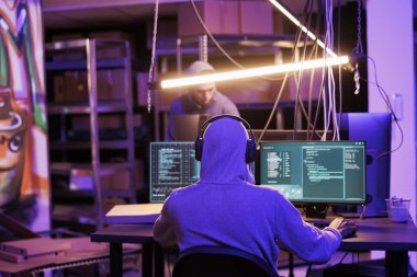 Bilgisayardaki şifreyi kırarken kulaklıklı hackerlar müzik dinliyor. Kulaklıklarda internet suçlusu çevrimiçi dolandırıcılık planlıyor ve neon ışığı olan bir yerde casus yazılım kodluyor.