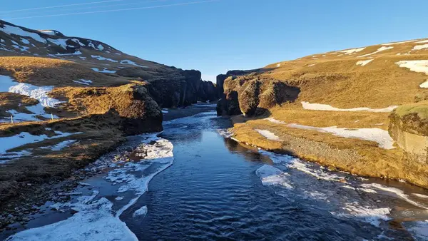 雪に覆われた山の間を流れる凍った水の流れを持つアイスランドの峡谷は 魔法の設定を作成します アイスランドの川 観光のマジカルフィドラグジュアリーキャニオン — ストック写真