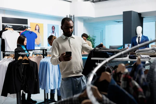 Afrikai Amerikai Férfi Ruhát Vásárol Ruhaboltban Ellenőrzi Méreteket Okostelefon Alkalmazásban — Stock Fotó