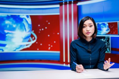 Haber odasında son haberleri sunan TV muhabiri, dünya çapında günlük olayları ve olayları sunuyor. Asyalı kadın gazeteci uluslararası televizyon kanalında flaş haber bölümünü sunuyor..