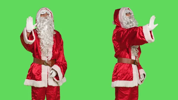 圣诞老人的角色扮演会举起手掌说不 在工作室里展示出带有绿色屏幕的停车标志 穿着圣爪服装的男人在镜头前做拒绝和拒绝的标志 圣诞节前夕的概念 — 图库照片