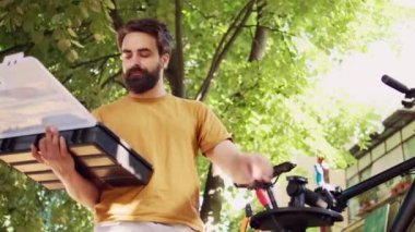 Motive olmuş beyaz adam bahçede bisiklet bakımı için alet çantasından özel ekipmanlar ayarlıyor. Bisiklet tamirhanesinde profesyonel iş aletleri düzenleyen kendini adamış genç bir erkek..