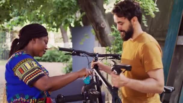 Αθλητικός Καυκάσιος Που Κουβαλάει Ποδήλατο Και Αφρικάνικη Αμερικάνικη Κυρία Που — Αρχείο Βίντεο