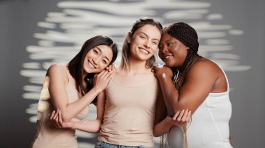 Interracial friends expressing body acceptance and woman power, feeling beautiful with luminous skin on camera. Happy flawless girls embracing body imperfections, curvy and skinny ladies.