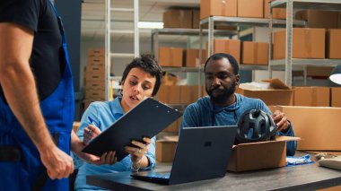 Team of startup owners packing merchandise in carton boxes and doing quality control before shipping products. Young woman signing logistics files and man putting goods in packages. clipart