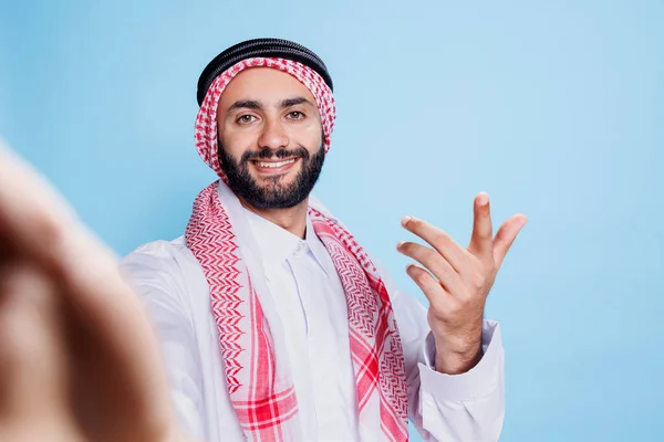 一个快乐的穆斯林男子穿着传统的衣服 从电视的角度出发打来电话 在网上交谈时 微笑着在现场的Arab人和看着前视镜的头巾 — 图库照片