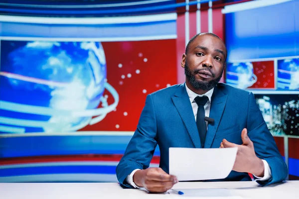 stock image Presenter delivering news from papers headlines, reporting exclusive information about latest events worldwide. African american news anchor transmitting details about business or politics.