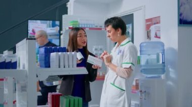 Eczacı eczane çalışanına ürün bilgilerini sorup reçeteli listedeki doğru maddeleri bulmaya çalışıyor. Hastalık ilaçlarını seçmede uzman eczacı.