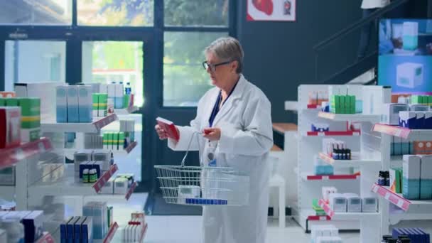 Ältere Erfahrene Pharmakologin Der Apotheke Hält Einen Warenkorb Und Sortiert — Stockvideo