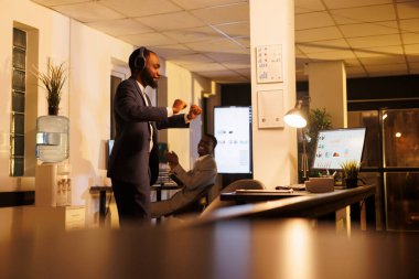 Neşeli menajer dans ediyor ve başlangıç ofisinde eğleniyor, iş molasında müzik dinlemekten zevk alıyor. Afrikalı Amerikalı iş adamı şirket yatırım stratejisini bitirdikten sonra dans hareketleri yapıyor.