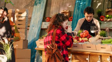 Kadın satıcı, bahçeden taze eko ürünler satmak için yerel sokak pazarında tüketiciyle konuşuyor. Çiftçi ve müşteri ev yapımı sebze ve sebzelere, sağlıklı ürünlere bakıyor. Üçayak atışı.