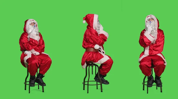 赤い衣装のキャラクターは椅子に座って 完全な体の緑色の背景に新しいアイデアを考えます スーツと白ひげでサンタのように振る舞う若いペンギングマン ブレインストーミングコンセプト — ストック写真