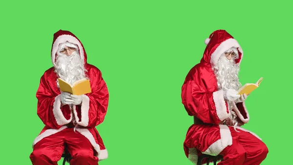 圣诞老人坐在椅子上看书 穿着节日红色服装的男人在绿屏背景下看书 圣诞老人喜欢童话故事 — 图库照片