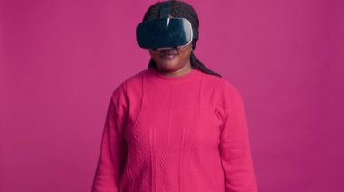 Yenilikçi genç siyahi kadın, stüdyoda sanal gerçeklik gözlüğü takarken interaktif cihazla fütüristik simülasyondan hoşlanıyor. Modern VR kulaklık kullanan Afro-Amerikan modacı.