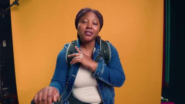 アフリカ系アメリカ人のバイクメッセンジャーが喜んで宅配便の仕事について説明するビデオ 自転車に乗った若い黒人女性が 食料配達サービスについてカメラで話す ハンドヘルドショット — ストック動画