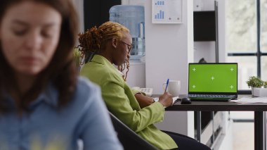 Krom anahtar telif alanı ekranlı dizüstü bilgisayar kullanarak bilgisayardaki yeşil ekran görüntüsünü analiz eden yönetici yardımcısı. Çalışma alanındaki izole edilmiş model ekrana bakan ofis çalışanı.