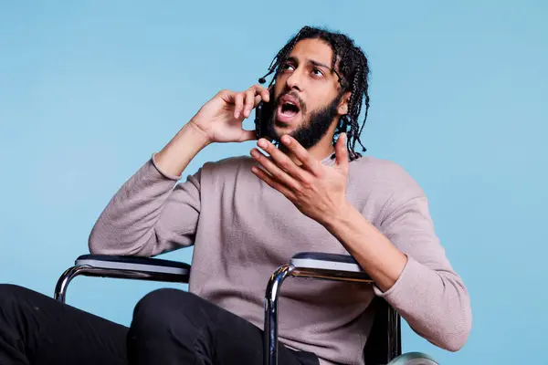 Homem Árabe Irritado Emocional Com Deficiência Falando Smartphone Enquanto Sentado — Fotografia de Stock