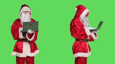 Saint Nick video konferansında dizüstü bilgisayar kullanıyor, çevrimiçi video konferansında insanlarla konuşuyor ve çevrimiçi sayfalara göz atıyor. Telekonferansta bilgisayar kablosuz bağlantısını elinde tutan modern kişi, yeşil ekran.