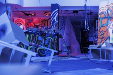 Çizimleri ve floresan ışıkları olan eski şehir binası, terk edilmiş paslı varoş mekanı mavi ve pembeyle aydınlatılmış ürkütücü görünüyor. İhmal edilmiş yer, parçalanmanın karanlığında parıldıyor..