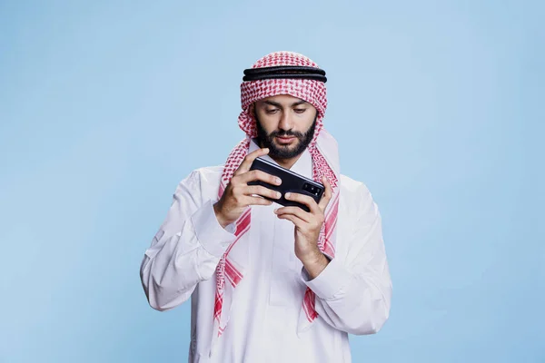 Мусульманин Традиционной Одежде Играет Онлайн Игру Смартфоне Позируя Студии Арабский — стоковое фото