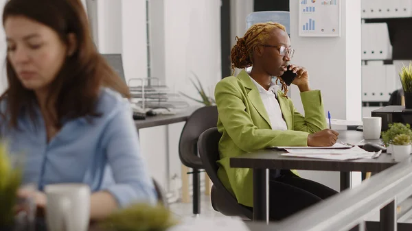 非裔美国成年人在创业办公室使用电话 与经理谈论投资计划 公司员工在工作场所进行远程交谈 在电话线路上聊天 — 图库照片