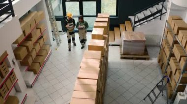 Depo işçilerinin karton kutuları inceleyip teslimata hazır olduklarından emin olmak için havadan drone görüntüleri. Depo çalışanları stokların ve envanterlerin iyi korunduğundan emin oluyor.