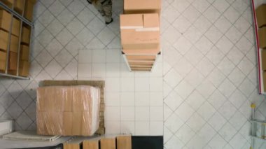 Deponun baş tedarik subayı karton kutuları paralel inceleyip bulguları karşılaştırıyor. Depo çalışanları stokların ve envanterlerin iyi organize edildiğinden emin oluyor.