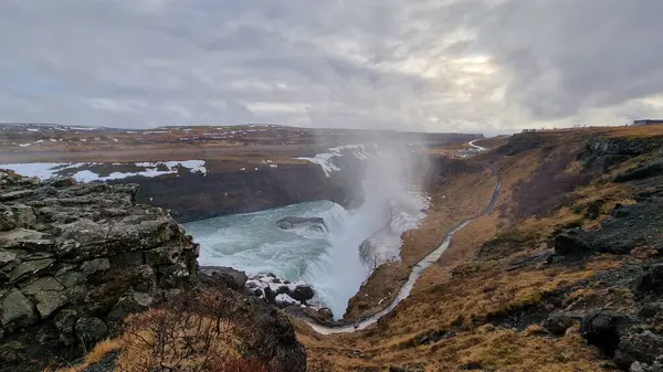 奇形怪状的古尔佛斯瀑布落在冰川带 雄伟的河水从结冰的山顶上倾泻而下 北欧自然呈现冰原 溪流中的瀑布从悬崖上奔流而下 — 图库照片