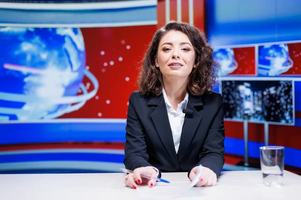 Woman presenter hosting news segment in newsroom, broadcasting live information from around the world. News anchor discussing about latest events on international television network.