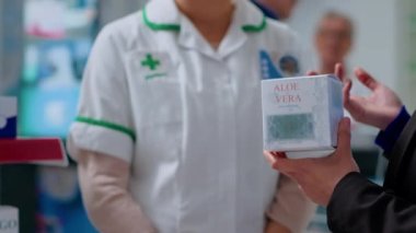 Dispanserdeki kaliteli eczacılara güneş yanıklarını tedavi etmesi için aloe vera ürünü sunuyoruz. Eczanedeki sağlık uzmanı müşteriye ağrı kesici merhemi konusunda yardım ediyor.