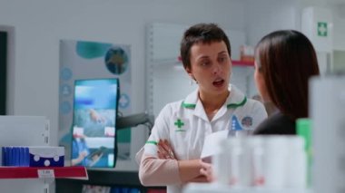 Dispanserdeki tanınmış eczacı güneş yanıklarını tedavi etmesi için Asyalı kadınlara aloe vera ürünü sunuyor. Eczacı dükkanında, müşteriye ağrı kesici losyonunda yardım eden bir sağlık uzmanı.