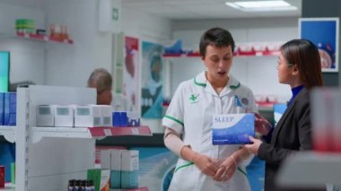 Eczanedeki bilgili eczacı uyku sorununu tedavi etmek için ilaç yazan bir hasta. Asyalı müşteri eczane çalışanından uykusuzluk ilacı alıyor