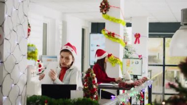 Heyecanlı bir çalışanın Noel hediyesiyle ilgilenen meslektaşı tarafından şaşırtılarak çekilen Dolly. Sevinçli personel işyerinde Xmas ışıkları ve çelenklerle süslenmiş Xmas hediyesi alıyor