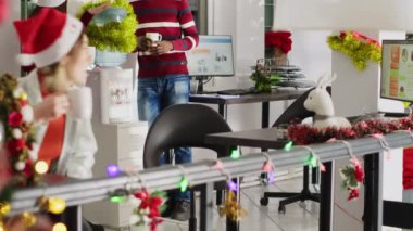 Noel süslemeli ofisteki şirket personeli su soğutucusunun yanında bir fincan kahvenin tadını çıkarıyor. Noel Baba şapkası takan kadın diğer personele katılıyor ve çok ırklı çalışma alanına giriyor.