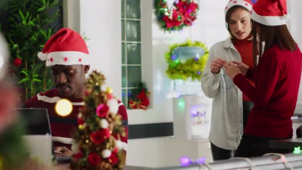 圣诞节的男人装饰办公室被那些在工作时背景嘈杂的工作人员分散了注意力 戴着圣诞礼帽的员工讨厌同事说得太大声 — 图库视频影像