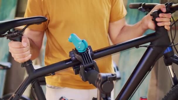 ヤードのメンテナンスのための専門の修理スタンドに自転車フレームを確保し 締める若者のクローズアップショット サービスのための自転車を慎重に実装し調整する人の詳細なビュー — ストック動画