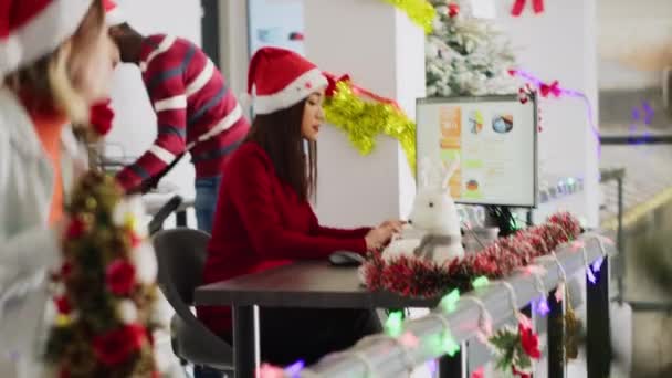 クリスマスオフィスで働くサンタの帽子をかぶっている従業員は 同僚の助けを求める Xmas Adornの職場 ハンドヘルドカメラで同僚とビジネス収入の数を見ているスタッフメンバー — ストック動画