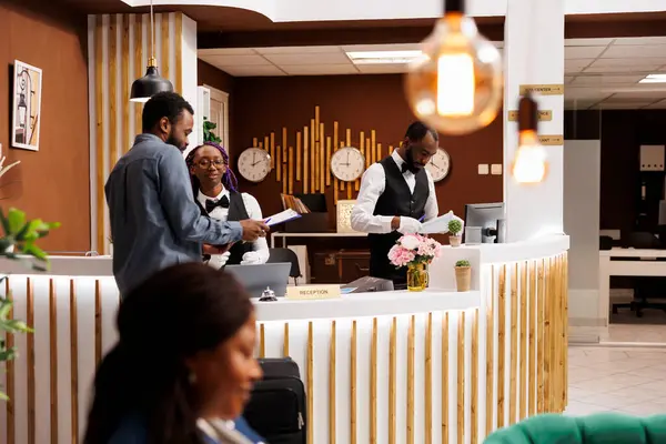 非洲裔美国人游客到达旅馆时 手持行李站在接待处填写报到表 在办理入住手续时 黑人旅客在前台签了名 — 图库照片