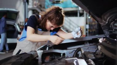 Garajdaki sertifikalı tamirci müşterinin arabasını tamir ediyor, kalan yağ sızıntılarını da araçtan çıkarıyor. Profesyonel, tamir atölyesinde müşteri otomobili temizliği yapıyor.