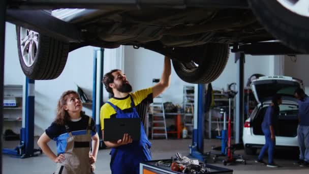 Znany Mechanik Klient Stojący Pod Samochodem Garażu Przy Użyciu Laptopa — Wideo stockowe