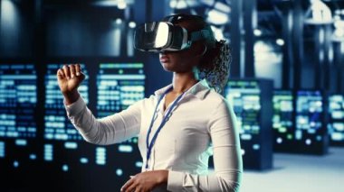 Afrika kökenli Amerikalı deneyimli bir uzman veri merkezinde sanal gerçekliğe dalmış, ünitelerin bakımını yapıyor. Sunucuların performansını optimize etmek, işlemleri kontrol etmek için VR kulaklığı kullanan usta bir profesyonel